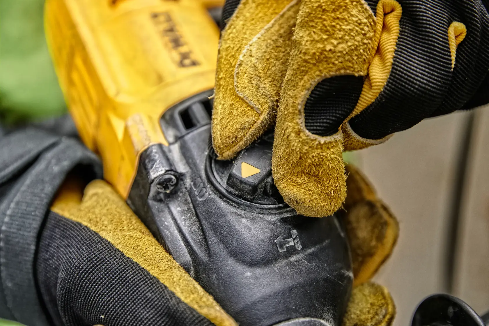 Close-up of a person wearing yellow and black work gloves adjusting the mode selector on a DEWALT power tool.