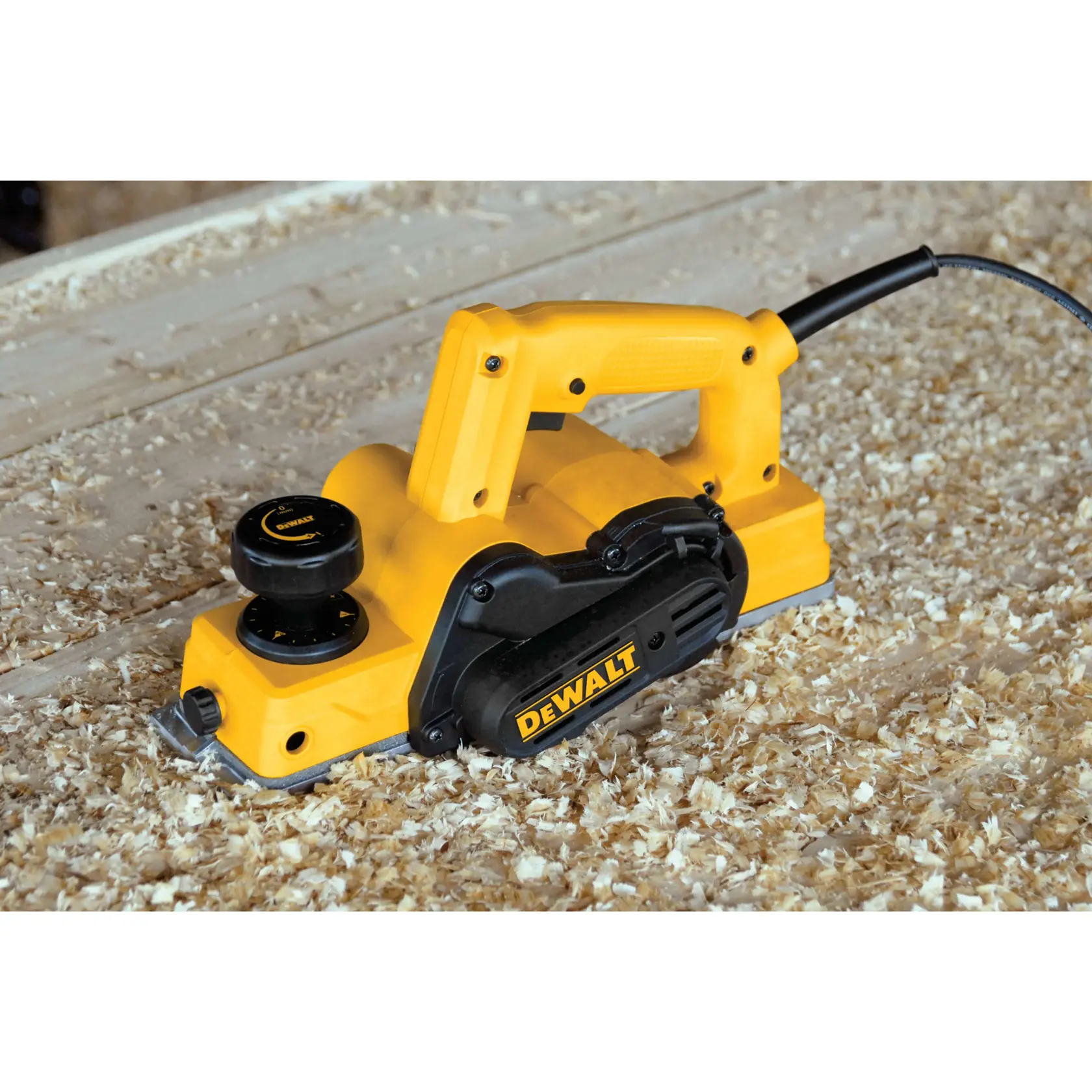 A yellow and black DEWALT electric hand planer is shown in use on a wooden work surface, surrounded by wood shavings.