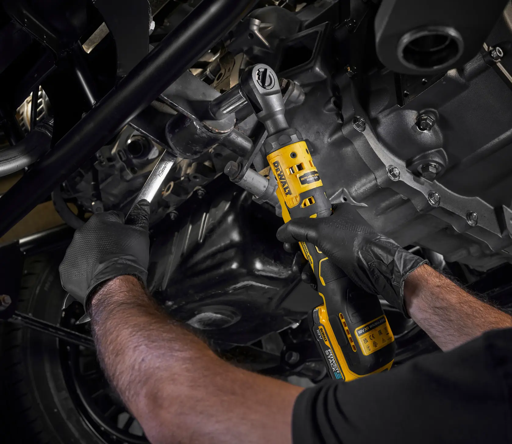 Photo of DEWALT DCF512N-XJ, DCF512N cordless ratchet in use on vehicle engine, user wearing gloves.
