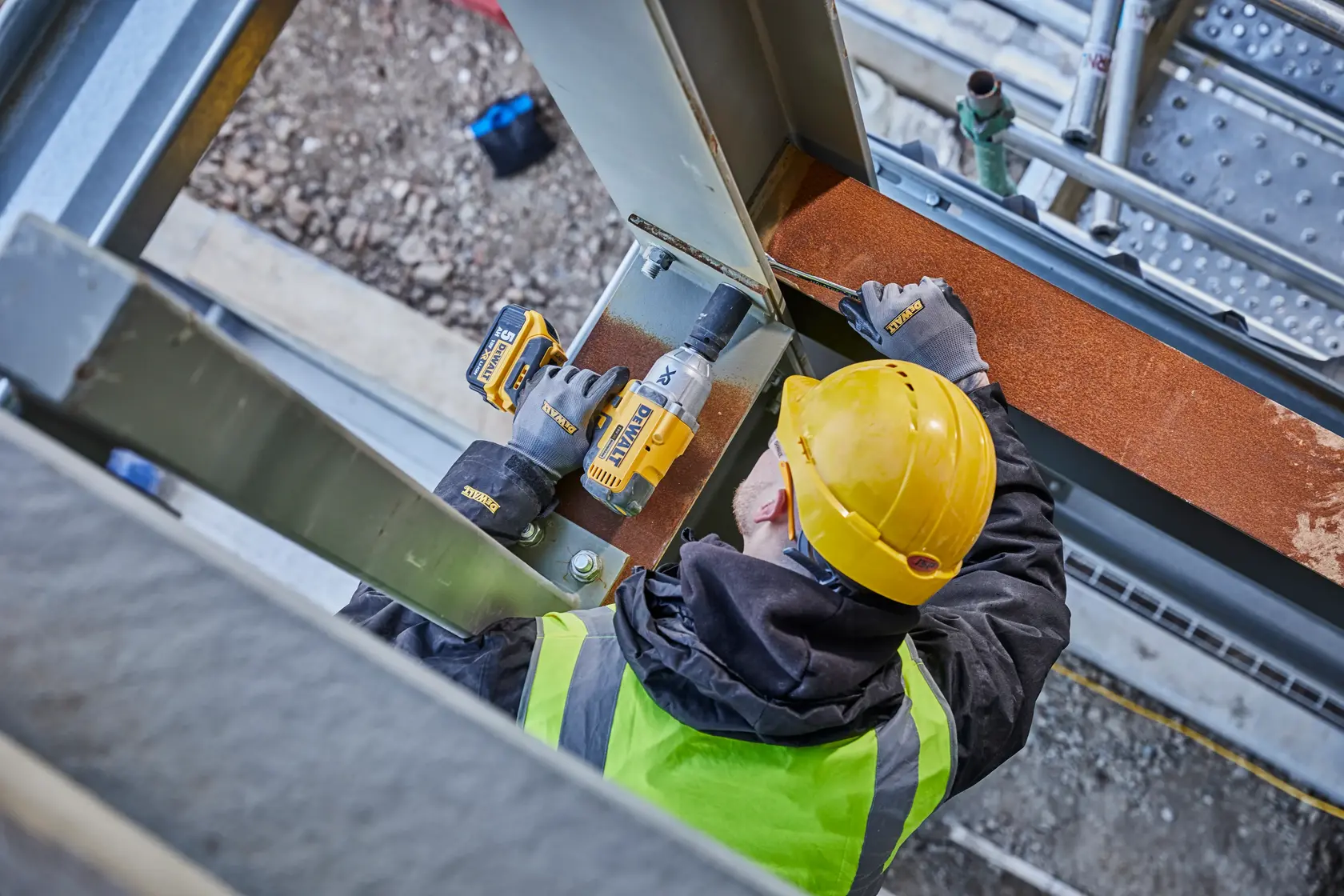 Worker uses DEWALT DCF897N-XJ, DCF897N tool on steel beam at site.