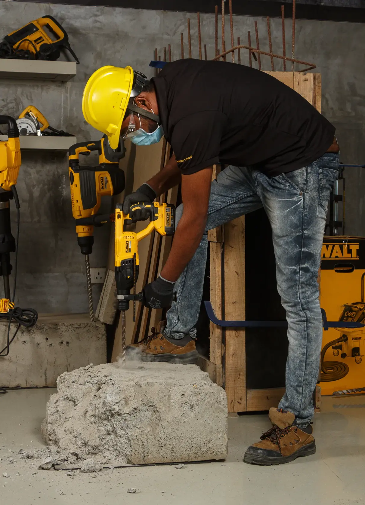 Worker uses a DEWALT DCH133NT rotary hammer drill on concrete, wearing safety gear in a construction setting.