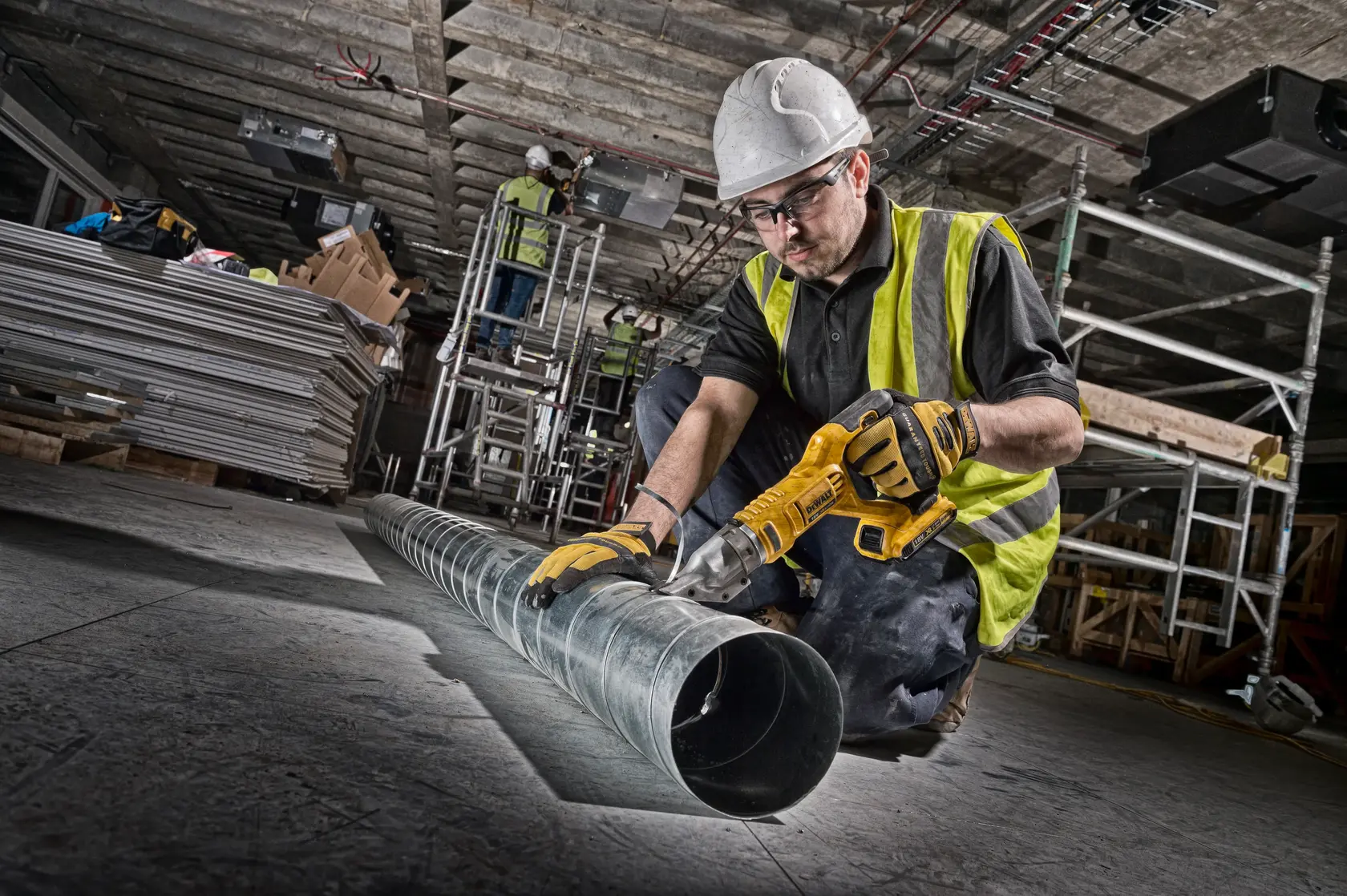 DEWALT DCS491NT-XJ and DCS491NT metal shear used in construction site, worker cutting duct pipe, high-vis vest, hard hat.
