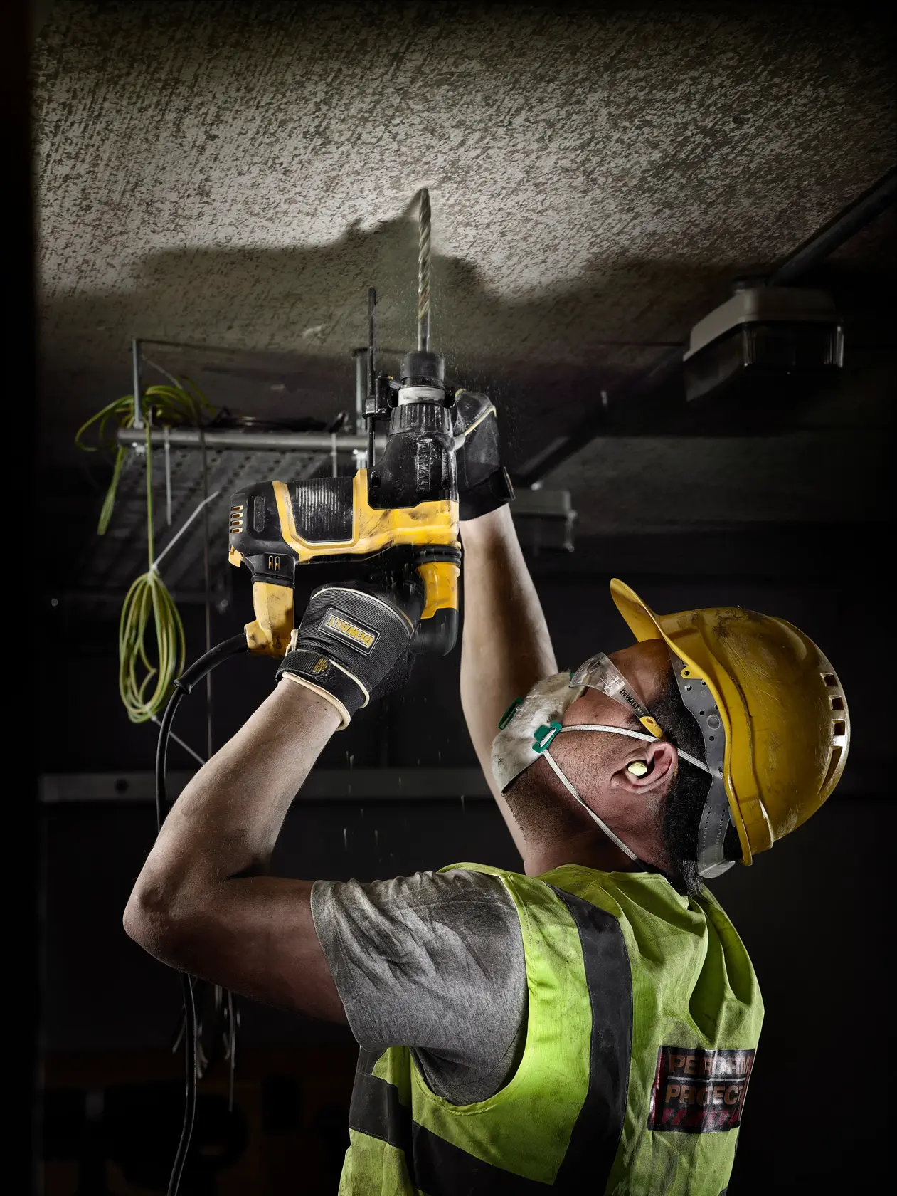 Worker using DEWALT DT9541, DT9541-QZ drill on ceiling at jobsite. Photography product category.