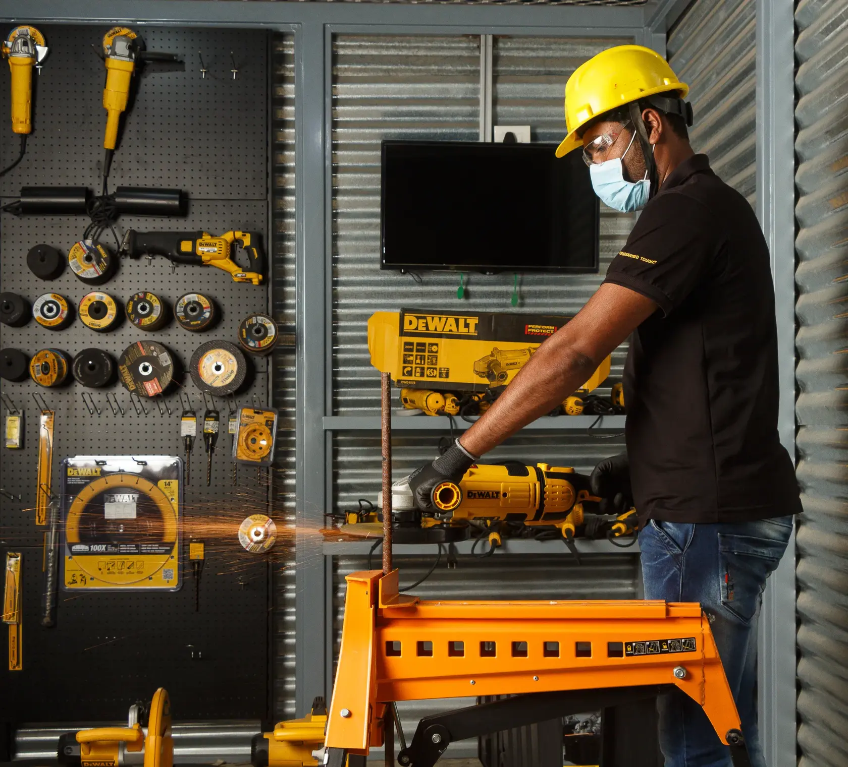 Worker uses DEWALT tool to cut metal in workshop, wearing safety gear. Displayed tools and equipment in background.