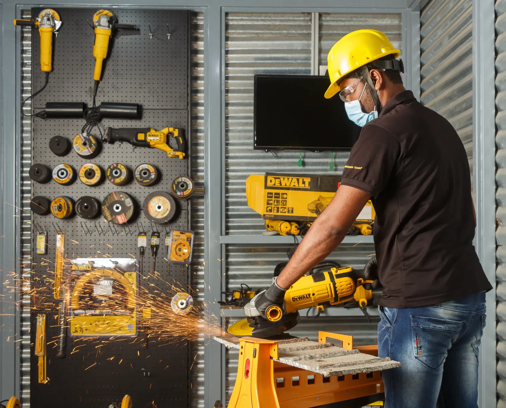 Person uses a DEWALT power tool to cut metal, with sparks flying. Tools and accessories are organized in the background.